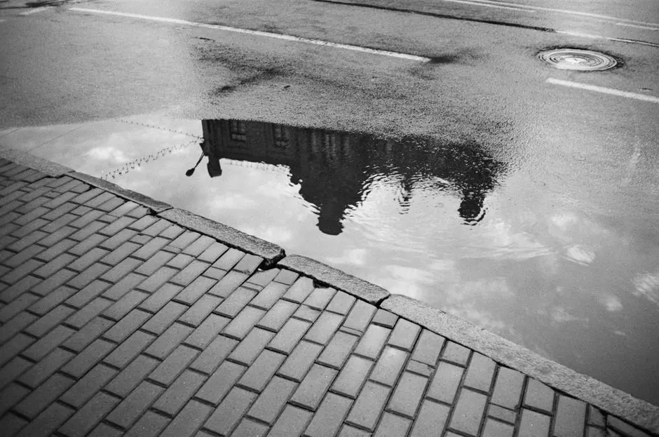 Grayscale image showcasing urban reflection in a puddle on Minsk streets.